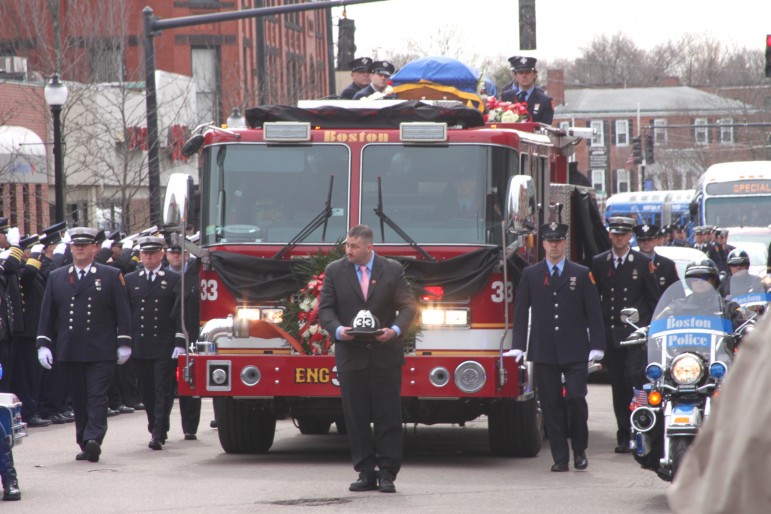 Fallen Boston Fire Lt. Edward Walsh's body is carried to the funeral on top of the fire engine on which he worked.