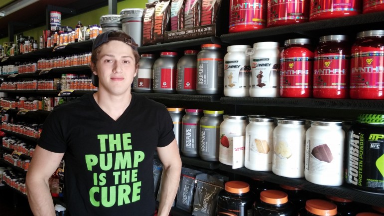 Connor Grimes, manager of AMP Nutrition Outlet, stands next to some of supplements sold at the shop on Arsenal Street.