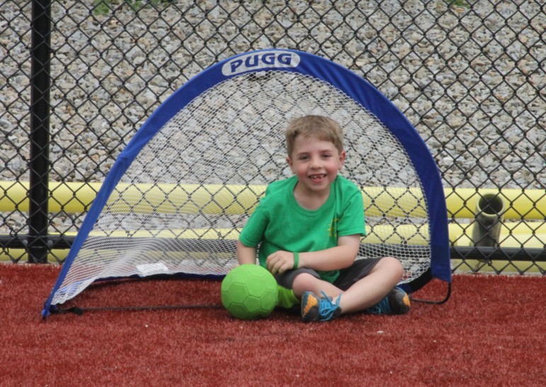 After kicking a ball in the net during Field Day, a student takes a rest.