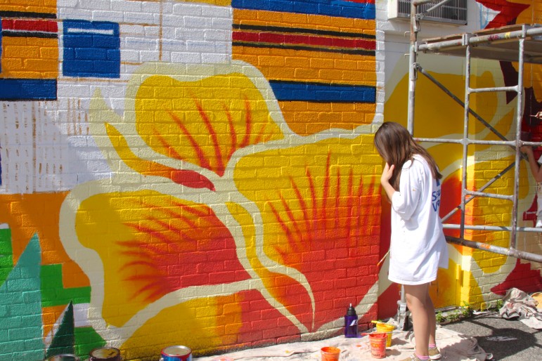 Watertown High School junior-to-be Emily Hart works on a floral section of the wall on Baptist Walk in Watertown Square.