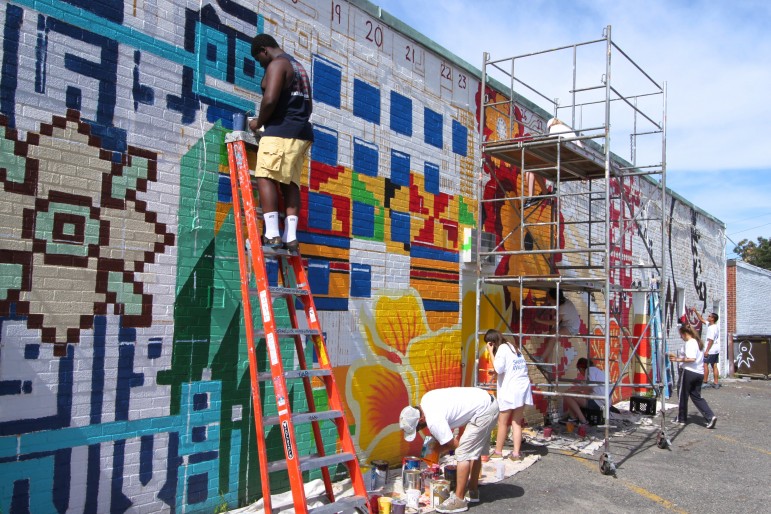 Watertown High School students, including senior Alain Mondesir (working on the ladder) work on the mural called "Tapestry of Cultures."