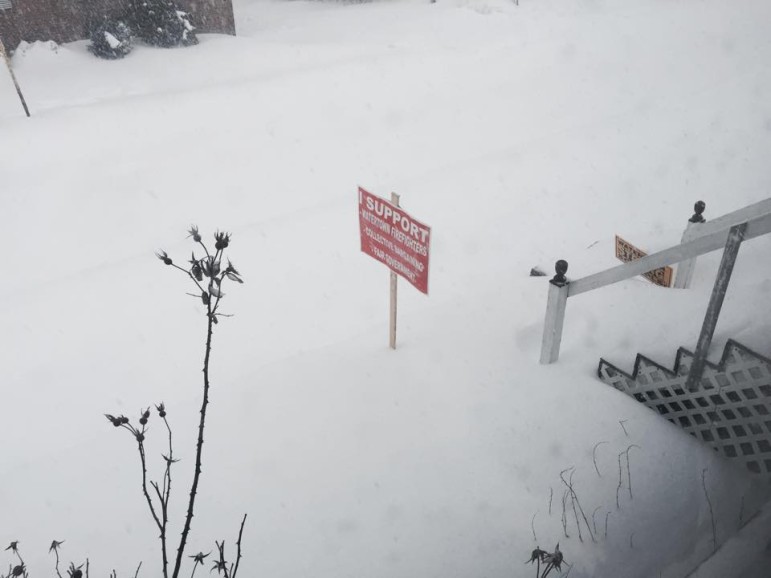 A "Support Watertown Firefighters" sign stands above the snow drift.