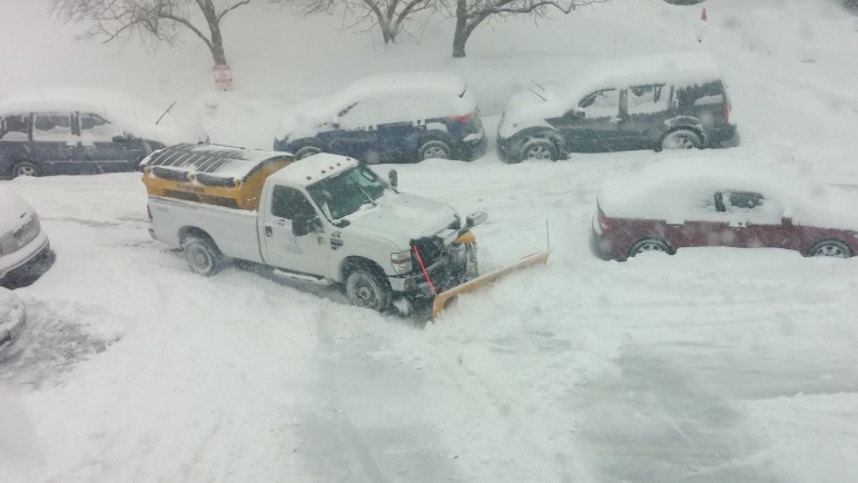 A snow plow clears snow from a parking lot.