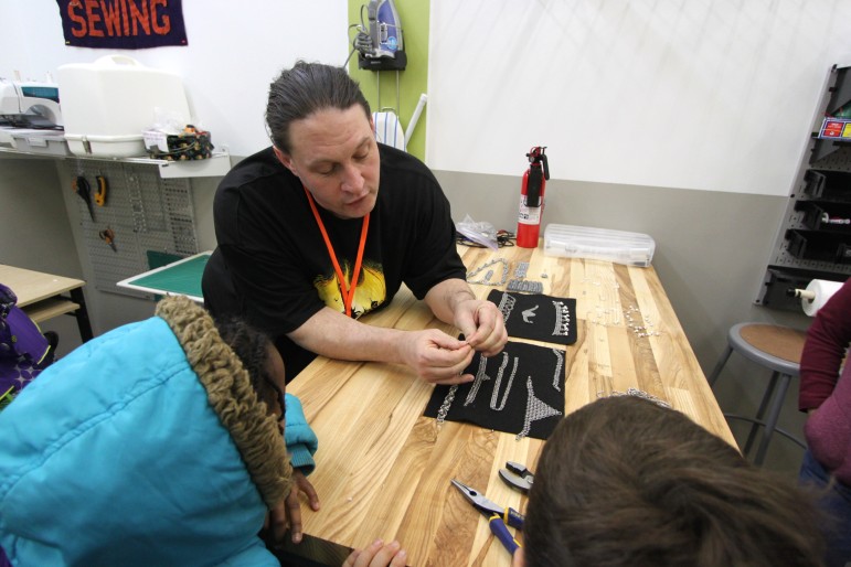 Chris Ernenwein shows children some of the jewelry and chainmail he made at HATCH.