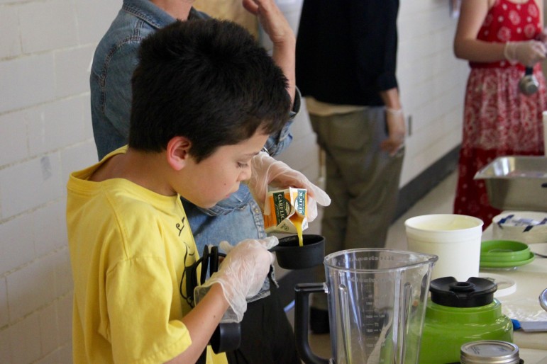 A Watertown student measures orange juice to make a berry smoothie. 