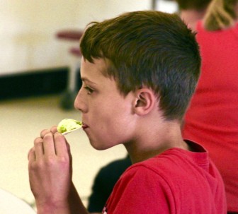A student enjoys a chip with creamy avocado dip made during a healthy eating event at Watertown MIddle School.