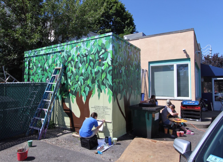 Watertown High School senior Julia Harrington puts the finishing touches on the mural on the refrigerator at Uncommon Grounds in Coolidge Square.