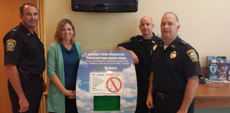 Lt. Michael Lawn (left), Dr. Laura Kehoe of Mass; General Hospital, Lt. Dan Unsworth and Interim Chief Ray DuPuis stand next to the new prescription drug drop box in the lobby of the Watertown Police Station. 