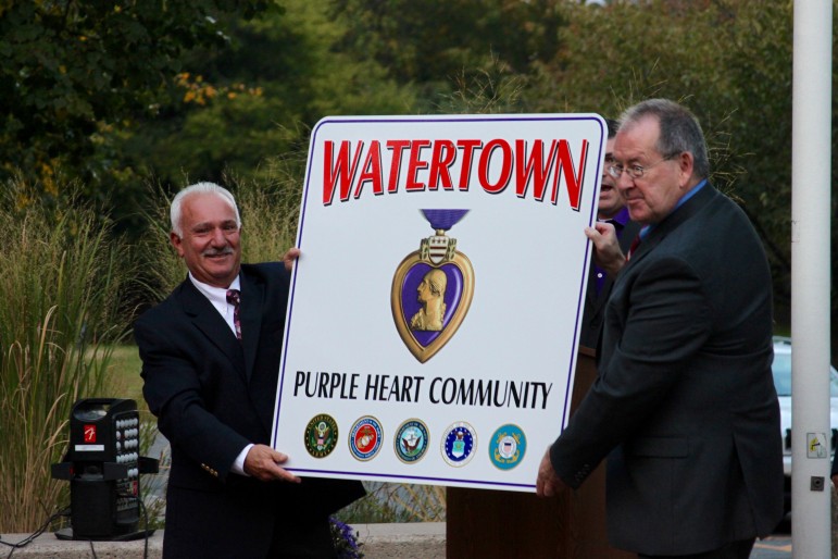 Town Council President Mark Sideris, left, and Town Manager Michael Driscoll hold the sign showing Watertown is a Purple Heart Town.