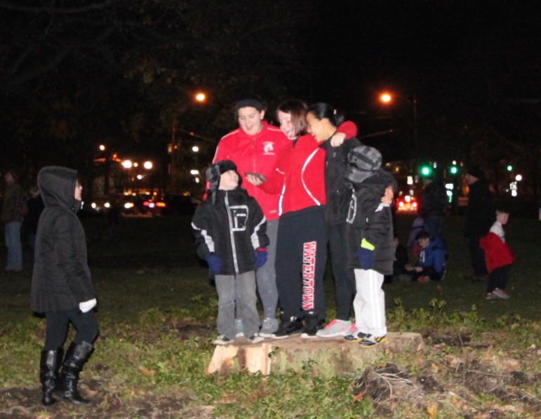 Children sing carols on top of the stump of an old tree removed this week. 