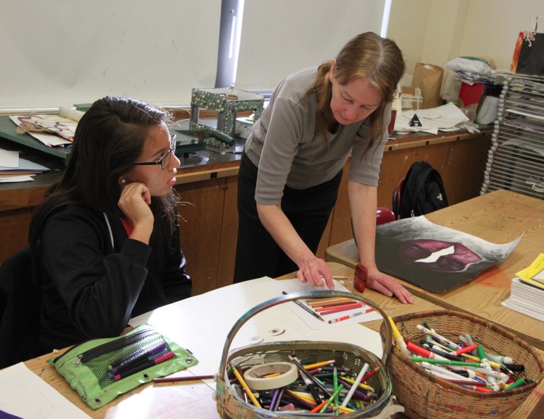Watertown High School art teacher Donna Cajella, right, works with senior Amanda Cardoso in the advanced art class.