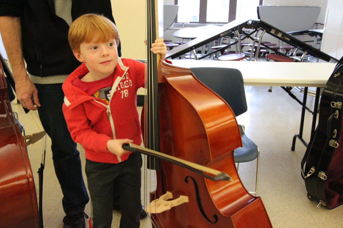 A kindergartner tries out a standing bass at the Instrument Petting Zoo.