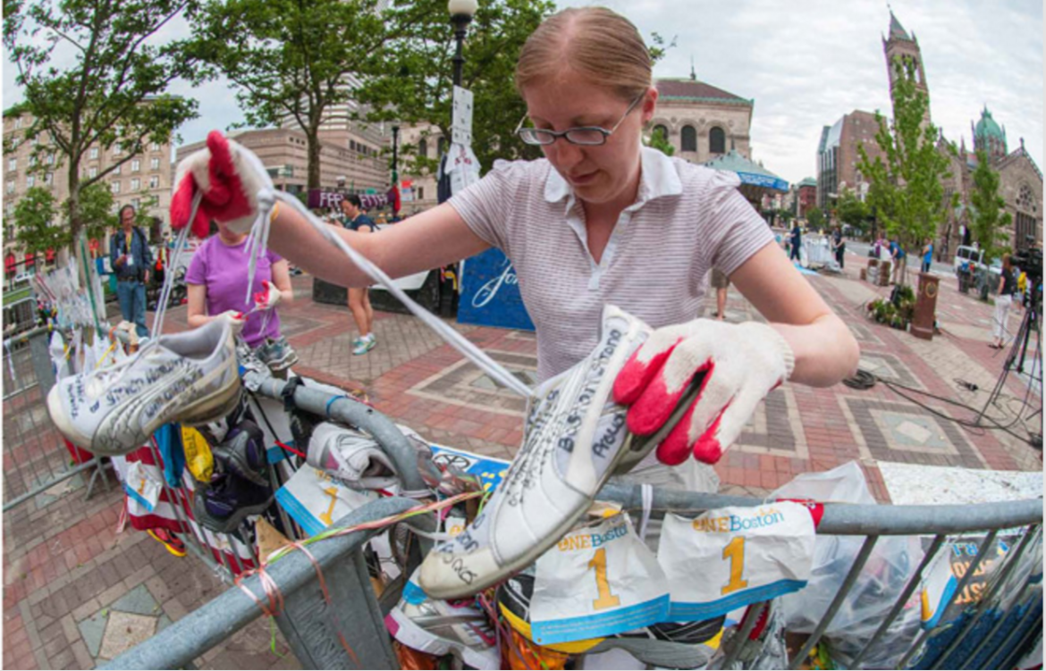 A woman dismantles the Boston Marathon Bombing memorial in Boston's Copley Square.
