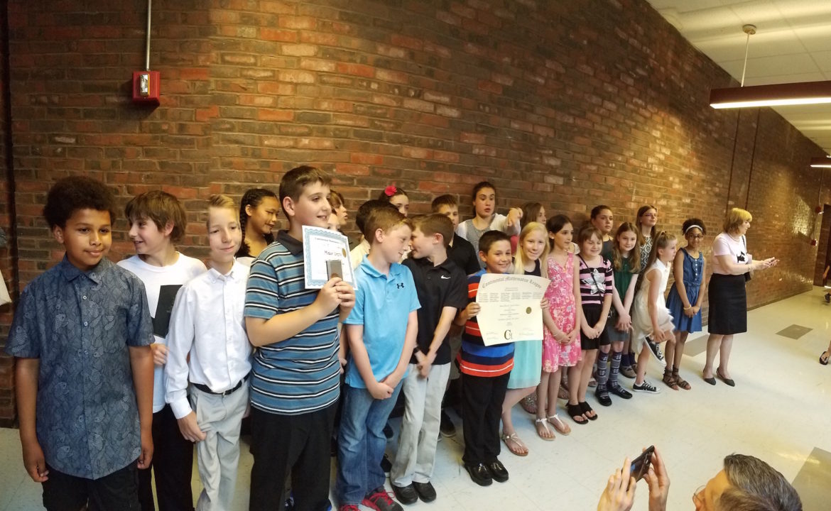 A panorama of the Lowell students who won the Continental Math League, including Mason Smith, in blue holding the certificate for getting a perfect score on all six tests.