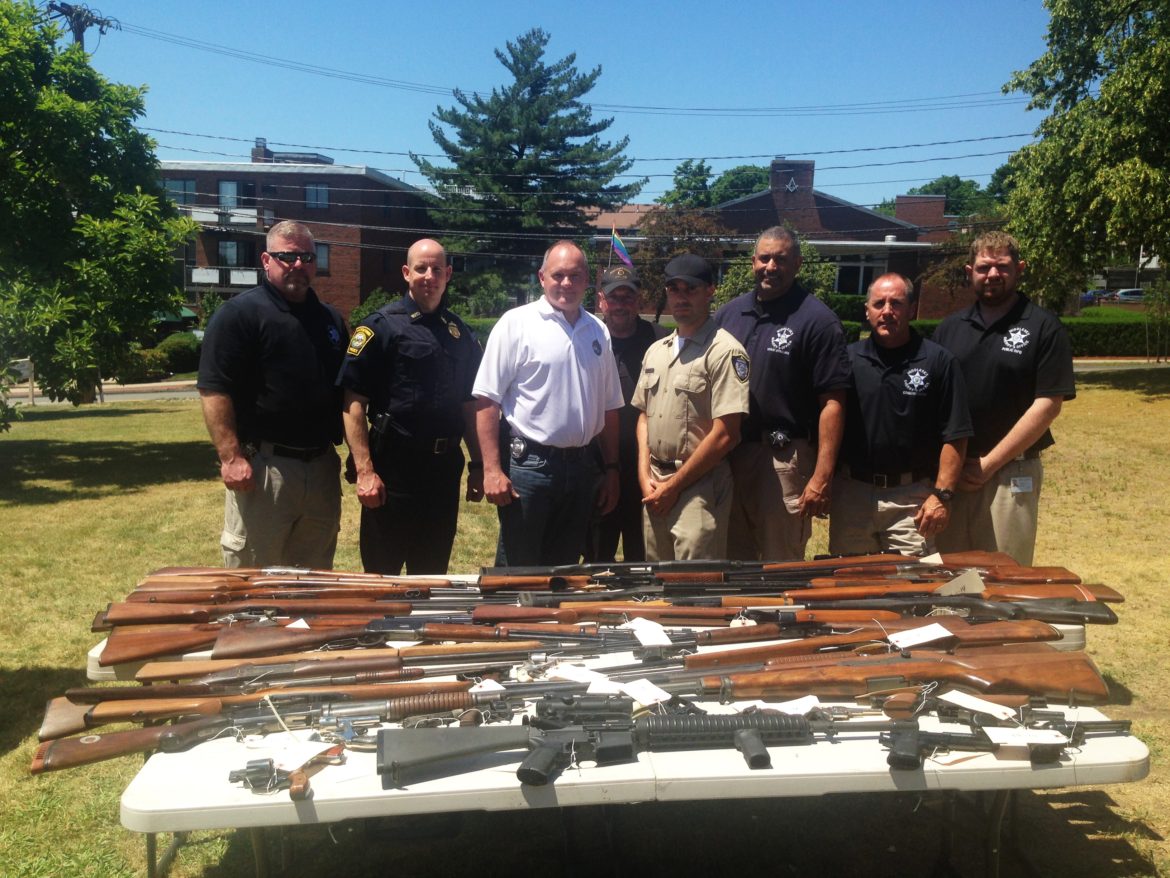 Members of the Watertown Police, the MIddlesex Sheriff's Office and the State Police pose with the 50 weapons collected in the gun buyback.
