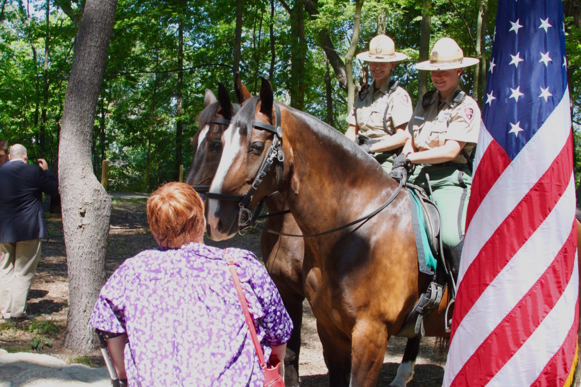 An attendee of the Watertown Riverfront Park ribbon cutting speaks with the horse mounted DCR Park Rangers.