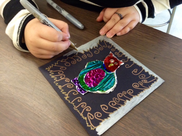A Hosmer student works on a Mexican hojalata art project, creating a frame for embossed metal art.